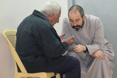 father_luis_montes_hears_confession_in_the_back_of_the_new_chapel_in_camp_virgin_mary_baghdad