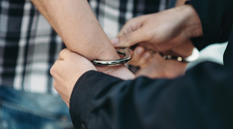 police-officer-puts-handcuffs-on-a-car-thief-qhglz58-800x445