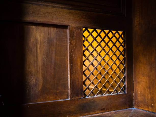 A closeup of a wooden window of the confessional box at church